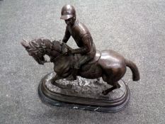 A bronze sculpture of a horse and jockey after Pierre Jules Mene, on a black marble base.