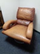 A tan leather swivel armchair on circular chrome base
