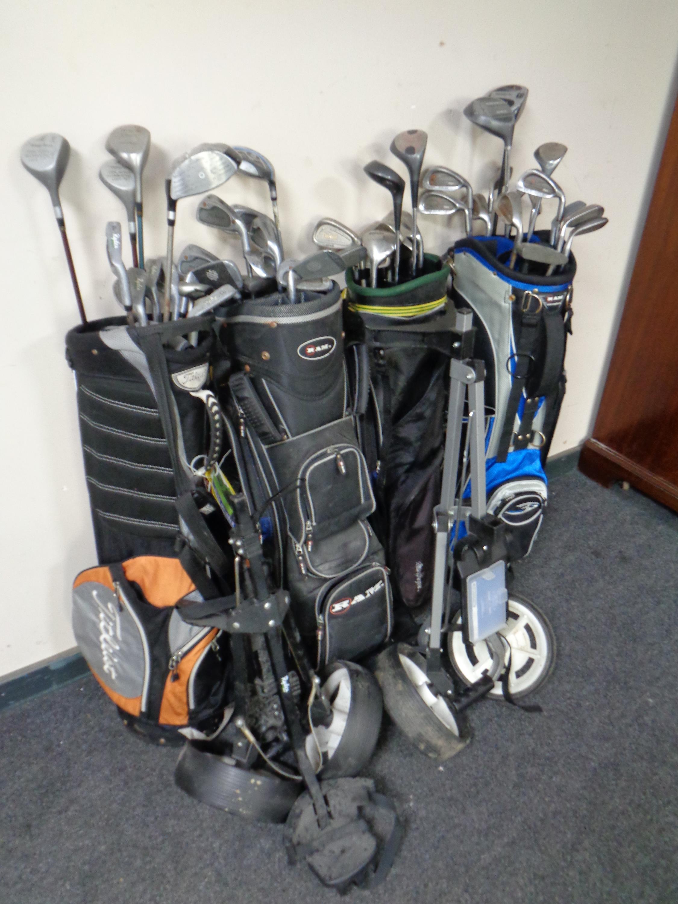 Four golf bags containing a large quantity of golfing irons and drivers to include Howson,