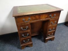 A mahogany kneehole desk fitted seven drawers with a green tooled leather inset panel