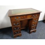 A mahogany kneehole desk fitted seven drawers with a green tooled leather inset panel