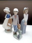 A Nao figure of a boy leaning on a stump with puppy, together with two further Nao figures of girls.