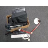 A box containing extension leads, camera tripods, angle poise lamp, laptop bag,