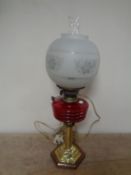 A Duplex brass oil lamp on wooden base with red glass reservoir,