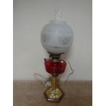 A Duplex brass oil lamp on wooden base with red glass reservoir,