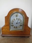 An Edwardian oak cased mantel clock with silvered dial on raised brass feet CONDITION