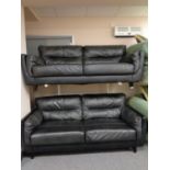 A pair of black leather two seater settees