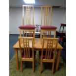 An extending rubber wood kitchen table together with six high back chairs in a pine finish
