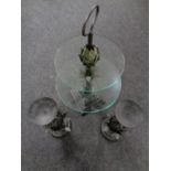 An ornate metal and glass two tier cake stand together with a further pair of metal candle holders