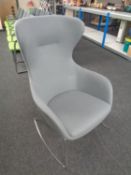 A contemporary wingback armchair on metal legs upholstered in a grey fabric