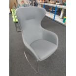 A contemporary wingback armchair on metal legs upholstered in a grey fabric