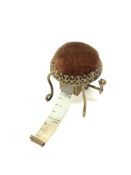 A late Victorian pin cushion sewing accessory in the form of a stool with tape measure under the