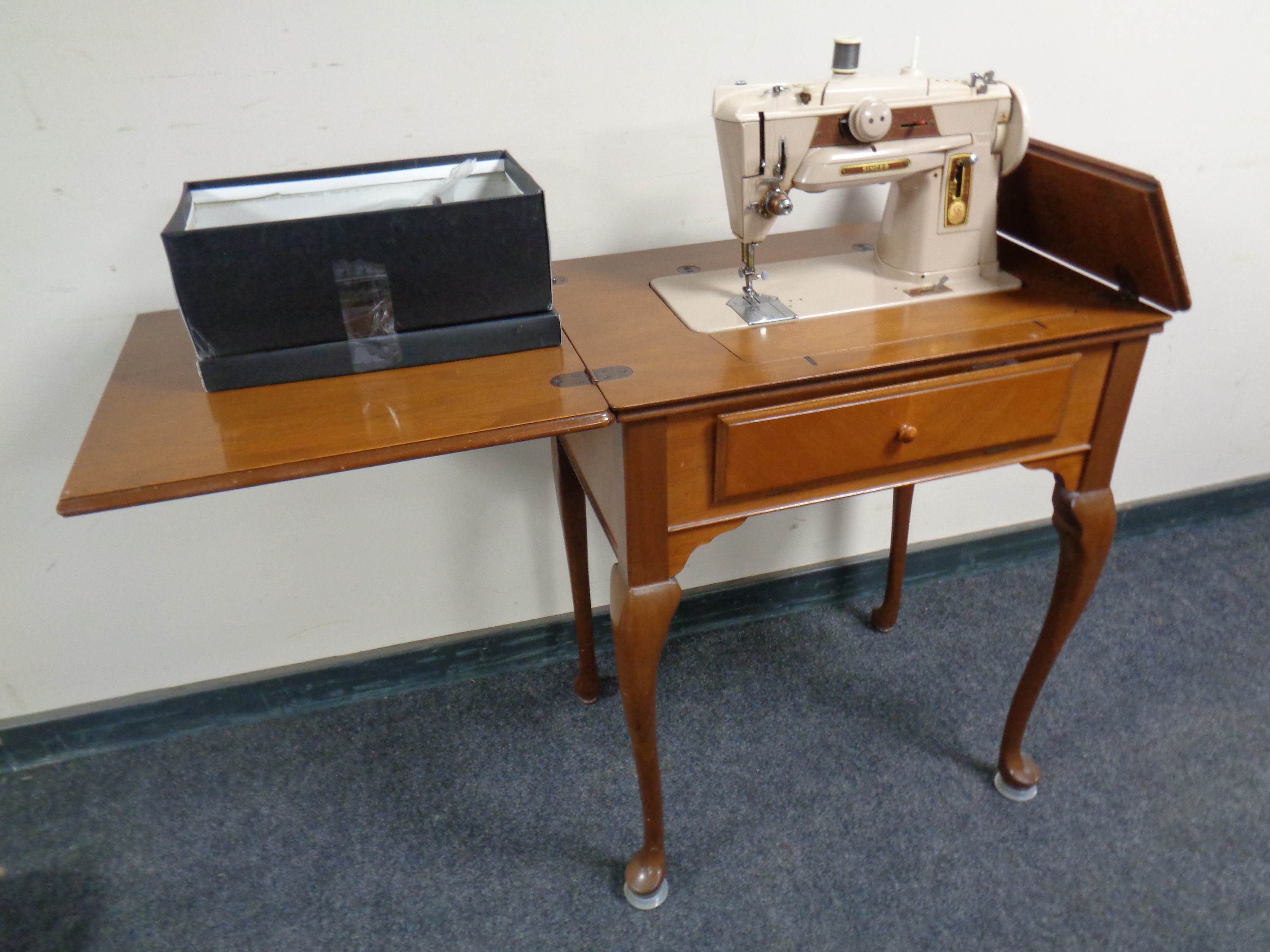 A mid 20th century Singer electric sewing machine in walnut Queen Anne table with accessories