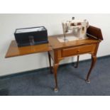 A mid 20th century Singer electric sewing machine in walnut Queen Anne table with accessories