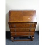 An early 20th century oak writing bureau fitted three drawers