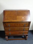 An early 20th century oak writing bureau fitted three drawers