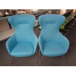 A pair of contemporary wingback armchairs on metal legs upholstered in a blue fabric