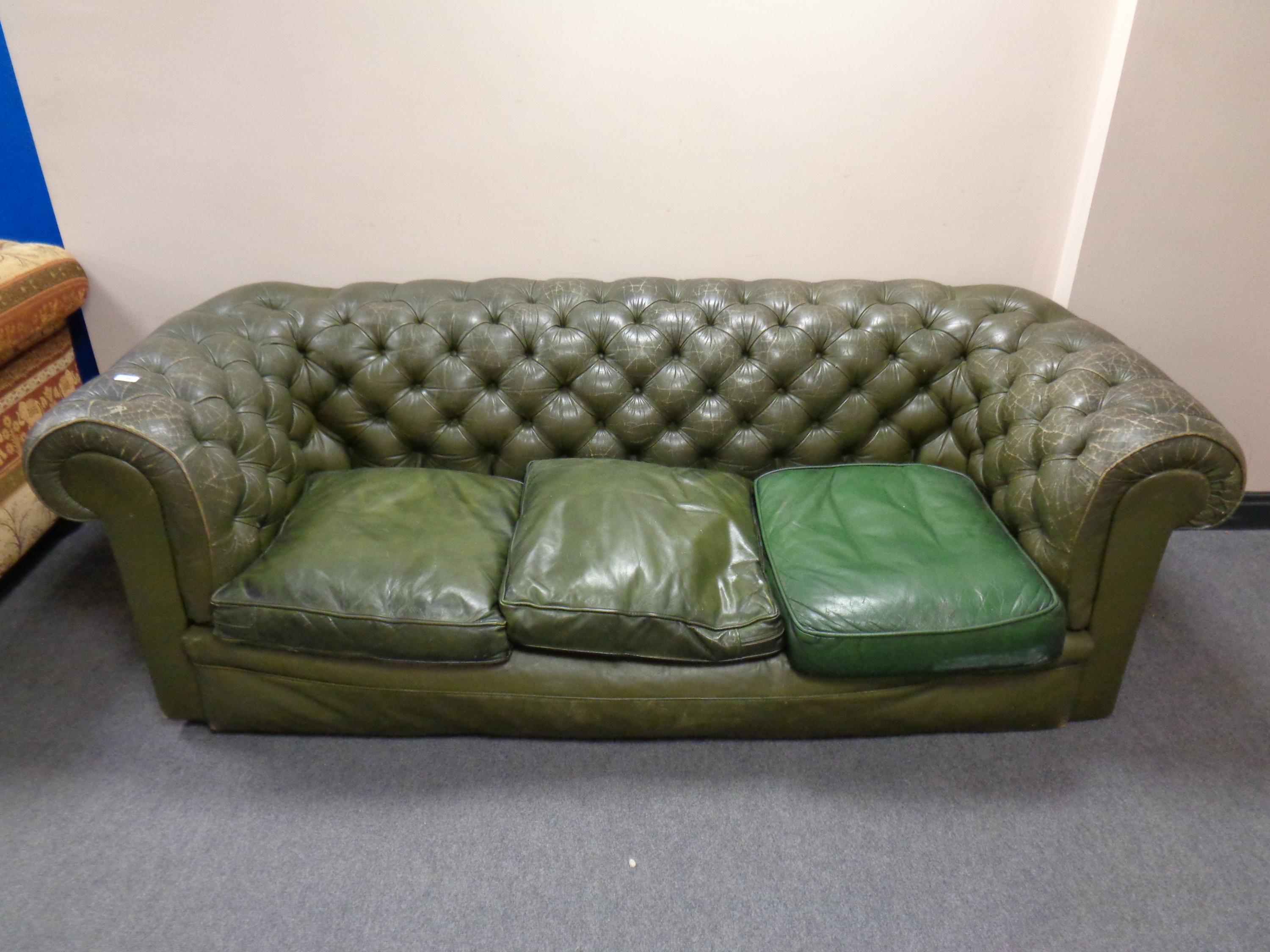 A green button leather Chesterfield three seater club settee (odd cushion)