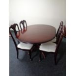 A circular extending pedestal dining table together with a set of four Queen Anne style chairs in a