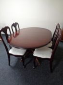 A circular extending pedestal dining table together with a set of four Queen Anne style chairs in a