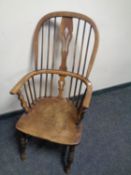 An antique elm Windsor high backed kitchen armchair