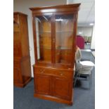 A Bradley Furniture reproduction yew wood glazed double door bookcase fitted cupboard and drawer