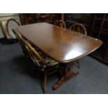 An Ercol solid elm and beech refectory dining table with four chairs in an antique finish