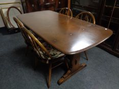 An Ercol solid elm and beech refectory dining table with four chairs in an antique finish