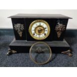 A 19th century cast iron mantel clock with brass and enamelled dial and metal mounts