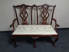 A reproduction Chippendale style two seater settee on claw and ball feet