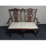 A reproduction Chippendale style two seater settee on claw and ball feet