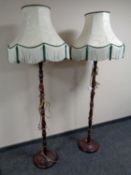 A pair of stained beech standard lamps with shades