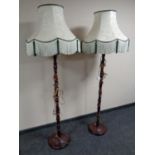 A pair of stained beech standard lamps with shades