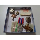 A box of assorted WWII medals, military cap badges,
