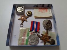 A box of assorted WWII medals, military cap badges,