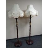 A pair of stained beech standard lamps with shades
