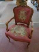 A carved beech framed French salon armchair upholstered in a tapestry fabric (damaged)