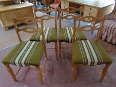 A set of four blonde oak dining chairs upholstered in a green striped fabric