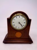 An Edwardian inlaid mahogany mantel clock with enamel dial on raised brass feet