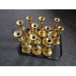 A tray containing five pairs of antique brass candlesticks