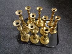 A tray containing five pairs of antique brass candlesticks