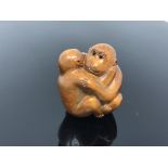 A carved hardwood netsuke - Two monkeys embracing