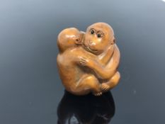 A carved hardwood netsuke - Two monkeys embracing