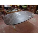 An oval composite coffee table on a heavy brass base