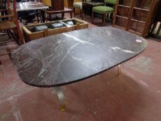 An oval composite coffee table on a heavy brass base