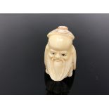 A carved bone netsuke - bearded man wearing a cap