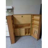 A teak effect double door ship's style cabinet containing bureau and shelves