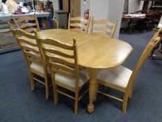 A contemporary pine pull out dining table together with six ladder back chairs