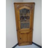 A good quality carved oak leaded glass door corner unit