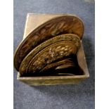 A brass embossed slipper box containing assorted brass plaques
